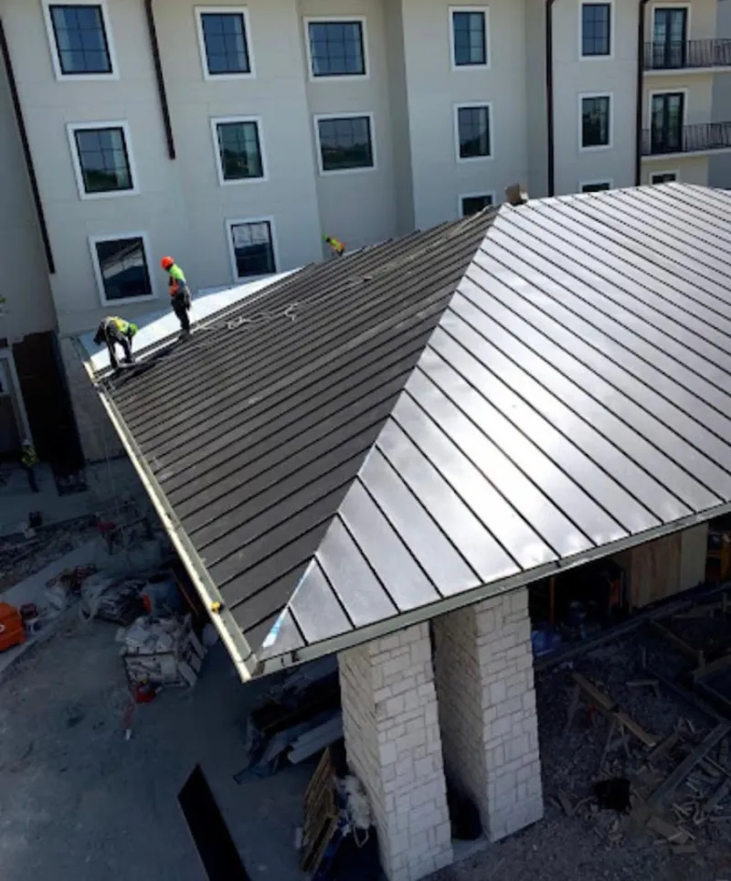Crew installing standing seam metal roof panels on a commercial project in Cold Spring
